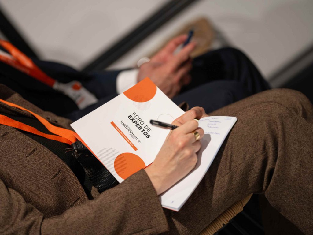 Fotografía del evento en Madrid del Instituto de Auditores internos. Tomando apuntes.